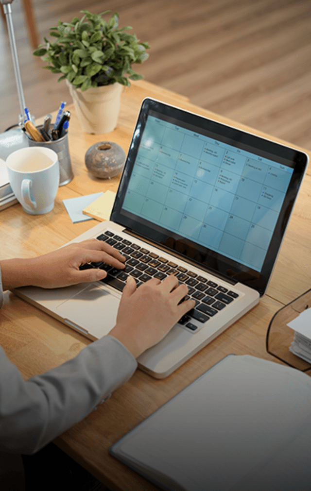 Mains posées sur le clavier d'un ordinateur affichant un calendrier